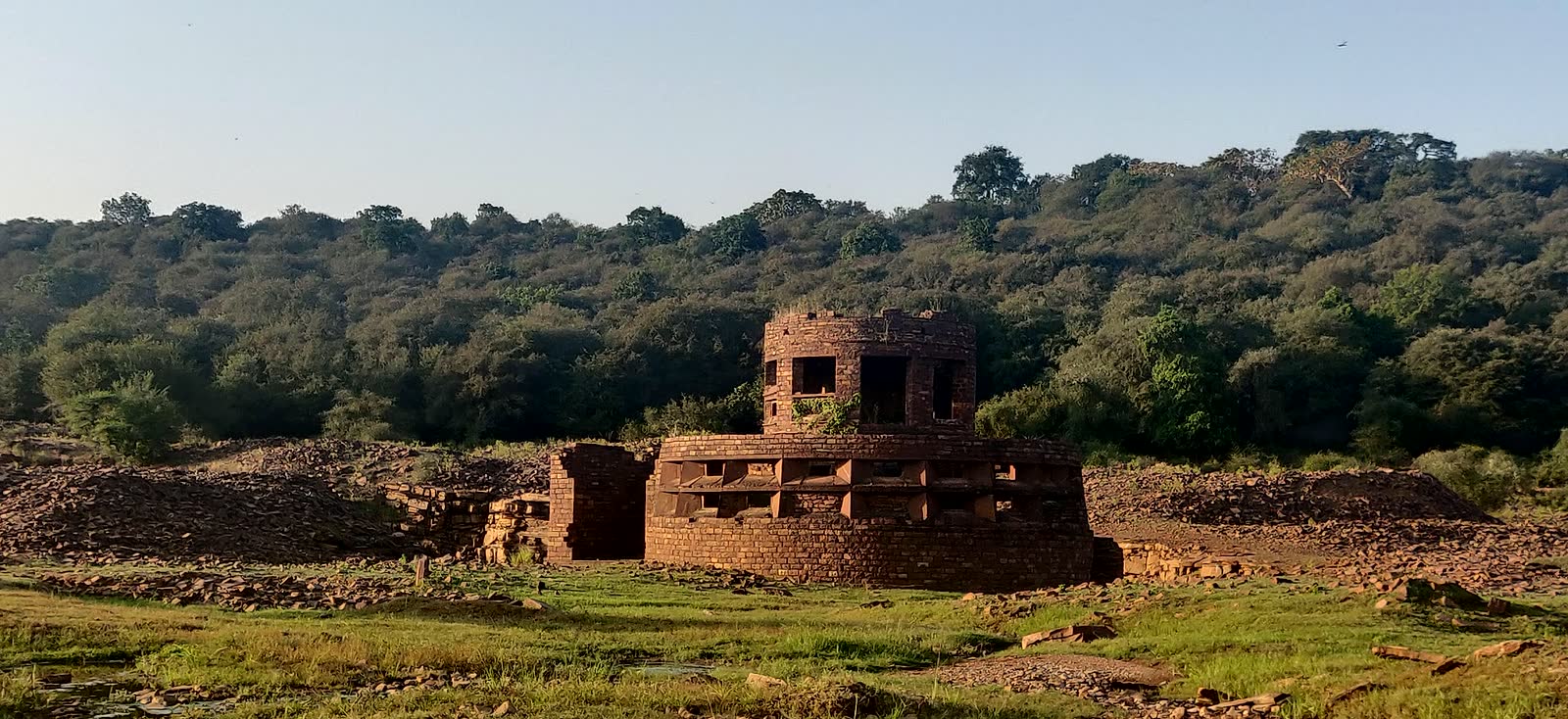 Old stone structure with hills and forest behind it
